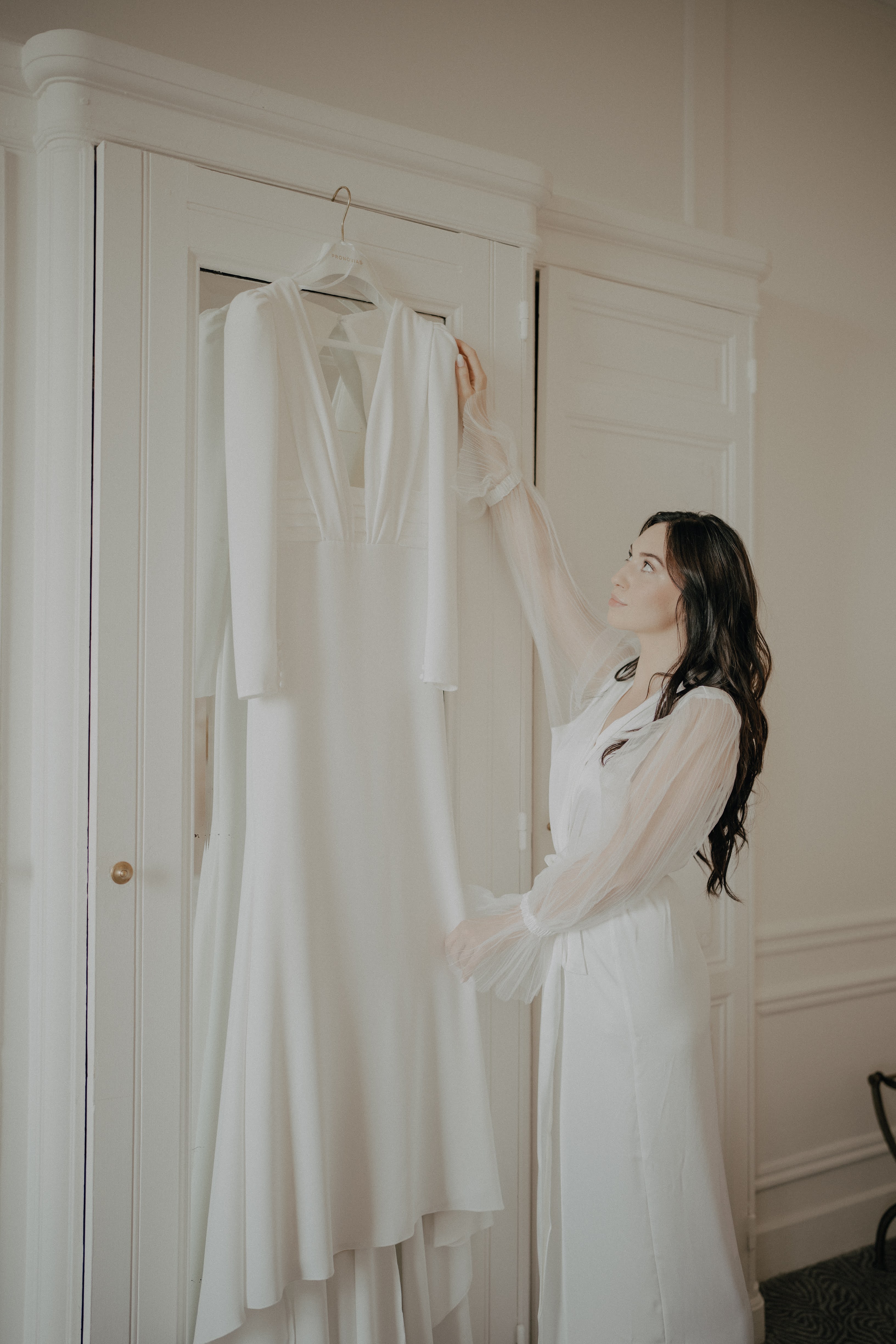 Mariée qui regarde sa robe accrochée